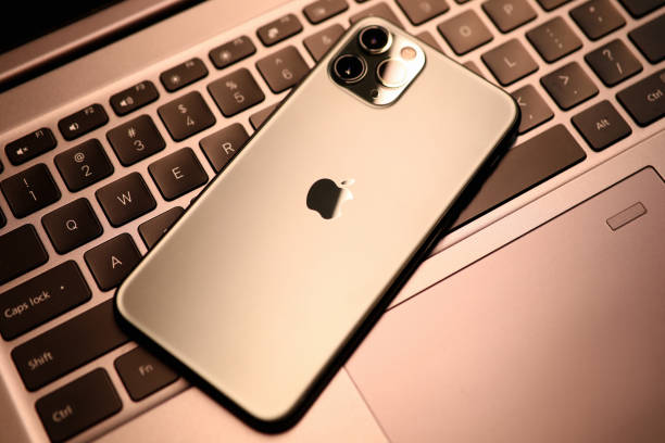 iphone pro d'apple sur le clavier d'ordinateur portatif - apple macintosh photos photos et images de collection