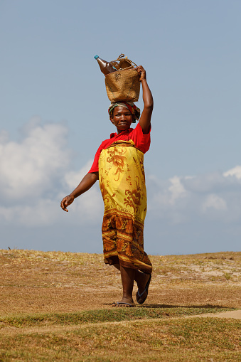 MAROANTSETRA, MADAGASCAR OCTOBER 20.2016: Malagasy woman carry heavy loads on head. The traditional method of transport of goods in Africa. October 20. 2016, Madagascar
