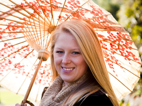 This pretty blond young adult shields herself from the sun with a colorful parasol