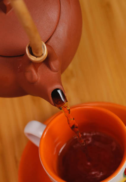 pouring tea from a teapot into a mug