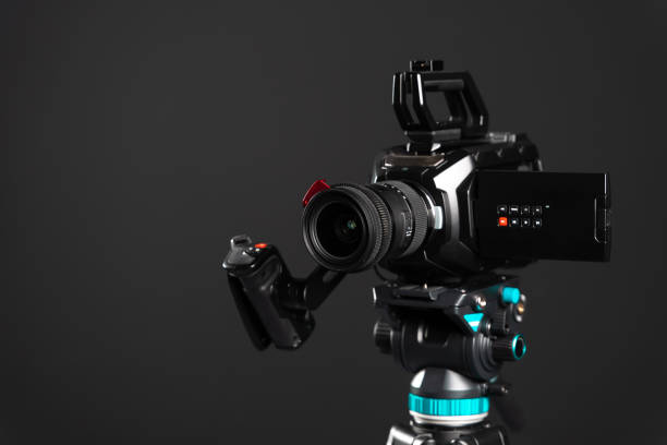 istock Professional video cinema camera on a camera tripod on black studio background copy space 1199165458