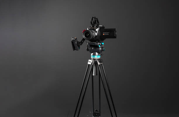 istock Professional video cinema camera on a tripod on black studio background copy space 1199165483