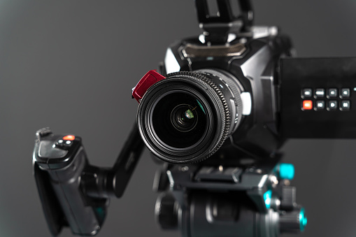 Professional video cinema camera on a camera tripod on black studio background copy space - close-up. The picture is taken with Sony A7III camera.
