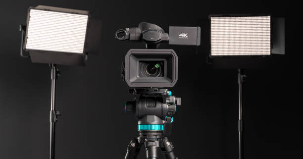 istock Professional 4K video camera on camera tripod and two lighting LED panel on black background 1199165691