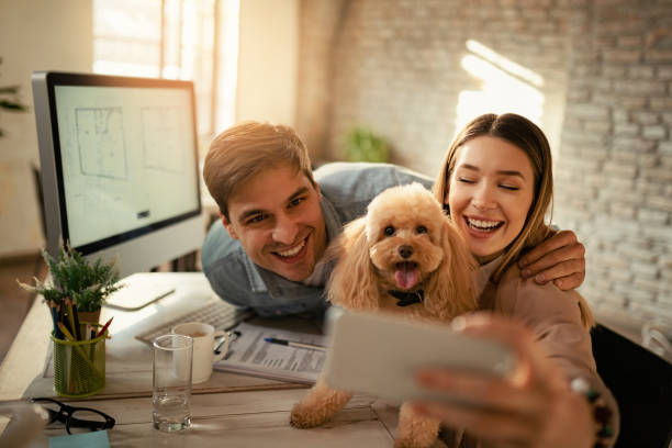 istock Happy colleagues taking selfie with a poodle in the office. 1199166541