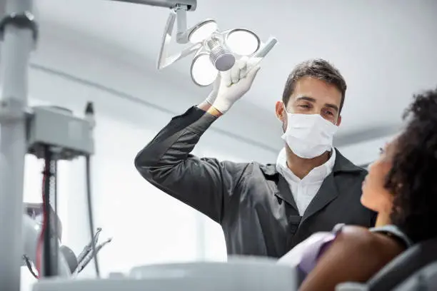 Photo of Dentist adjusting surgical light in dental clinic