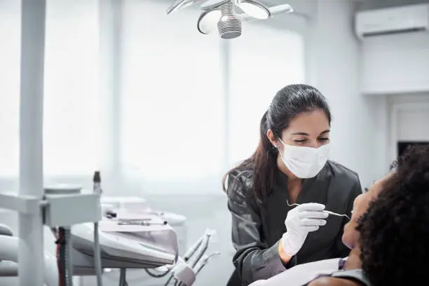 Photo of Female dentist examining patient in clinic