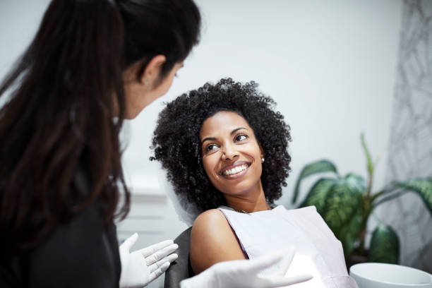 dentiste discutant avec le patient féminin de sourire - sourire à pleines dents photos et images de collection