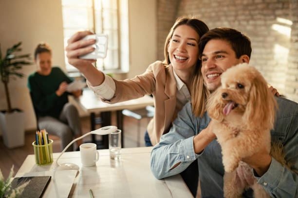 istock Happy freelancers taking selfie with a dog while working in the office. 1199168396
