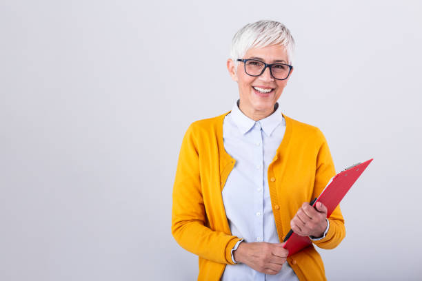 dojrzała kobieta biznesu trzymająca dokument na schowku i okulary izolowane na białym tle. poważna kobieta biznesu patrząc na dokumenty, trzymając okulary w drugiej ręce - mature women isolated mature adult women zdjęcia i obrazy z banku zdjęć