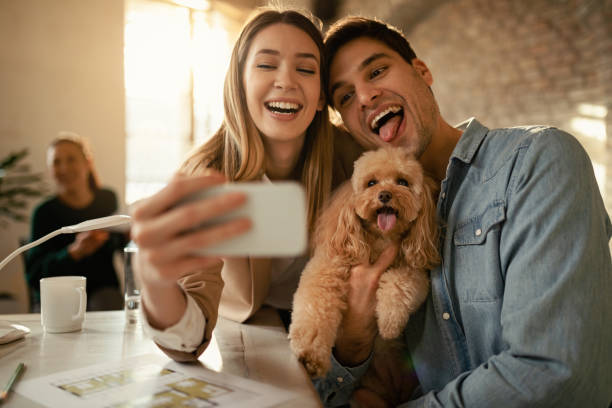 istock Playful freelance workers taking selfie with a poodle in the office. 1199168754
