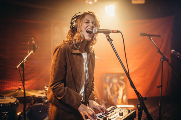 Lady musician playing keyboard One woman, beautiful young lady singer, singing in microphone, playing keyboard. singer stock pictures, royalty-free photos & images