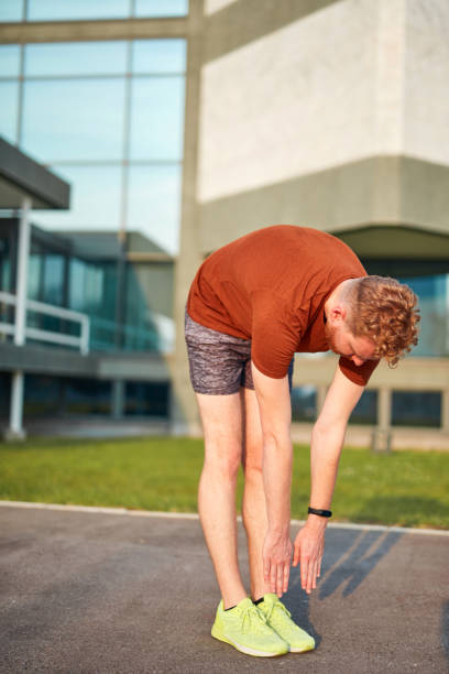 istock Young man exercising / stretching in urban park. 1199172170