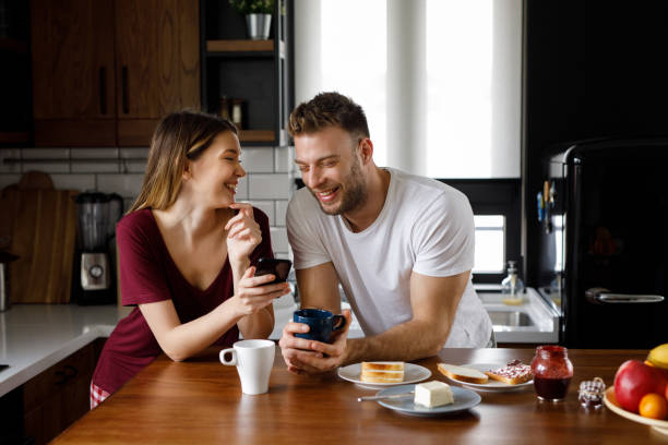istock Happy young couple using smart phone together during breakfast at home 1199174589