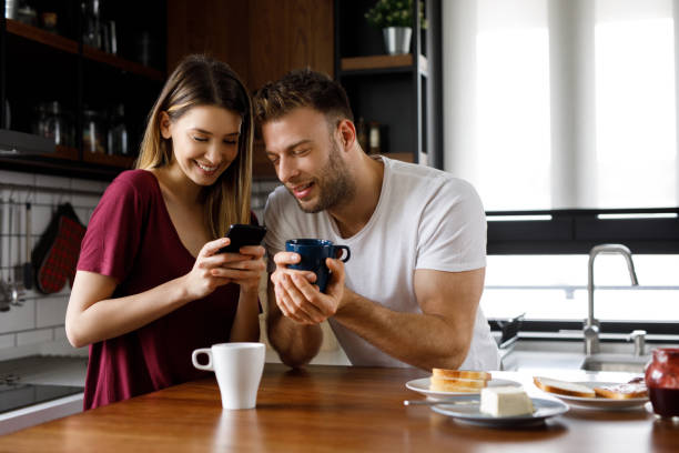 istock Happy young couple using smart phone together during breakfast at home 1199175585