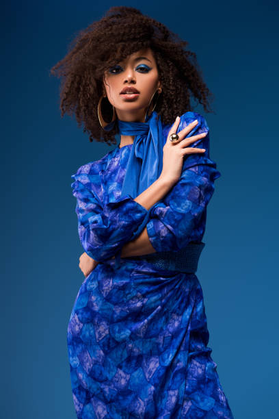 привлекательная афро-американская женщина в платье, глядя на камеру изолированы на синем - women dress black young women стоковые фото и изображения