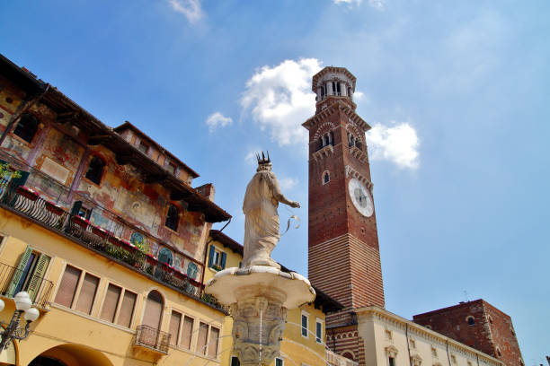 widok z tyłu fontanny posąg madonny i lamberti wieży z zegarami na placu erbe w weronie, włochy. torre dei lamberti nad błękitnym niebem, słynna wieża zegarowa na piazza delle erbe - torre dei lamberti zdjęcia i obrazy z banku zdjęć