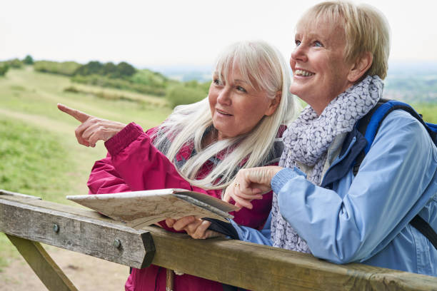 dos amigas de mujeres mayores en vacaciones a pie descansando en la puerta con el mapa - map uk hiking reading fotografías e imágenes de stock