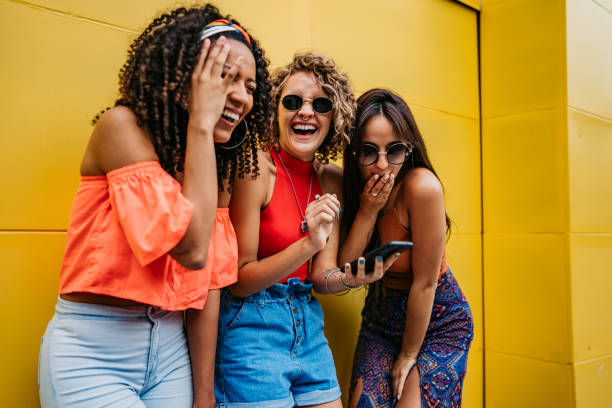 istock Three young women laughing and using phone 1199180162