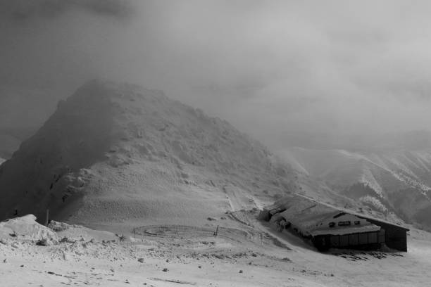 mau tempo na casa de campo da pedra no pico da montanha de chopok em tatras baixos em eslováquia. grande nevoeiro está chegando. venda de vento com nevoeiro é criado combinação letal. atmosphera muito deprimente - heat snow urban scene creativity - fotografias e filmes do acervo