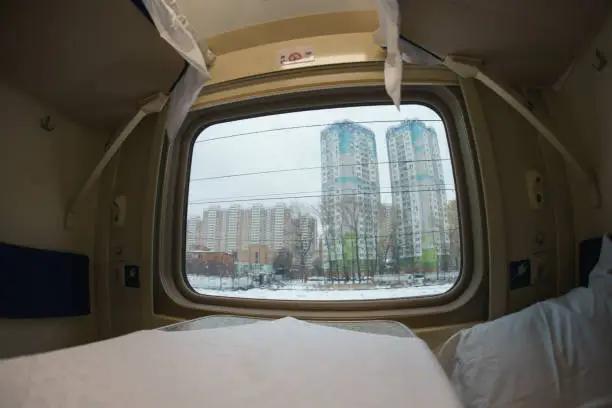 Photography of coupe interior of the long-distance train. New modern double-decker train. Touristic and travel concepts. Fish eye lens. Moscow uptown buildings - view through window.