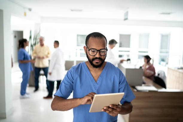 male nurse using digital tablet at hospital - nurse doctor scrubs male imagens e fotografias de stock