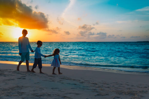 istock father and kids walking on beach at sunset 1199189242