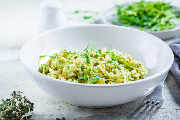 risotto verde con broccoli, piselli verdi e germogli in piatto bianco. concetto di cibo vegano sano. - leaf vegetable asparagus green vegetable foto e immagini stock