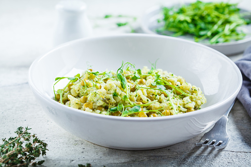 Green risotto with broccoli, green peas and sprouts in a white plate. Healthy vegan food concept.