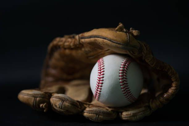 istock Baseball in a glove on black background. 1199190424
