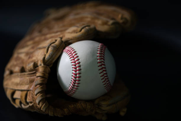 istock Baseball in a glove on black background. 1199190439