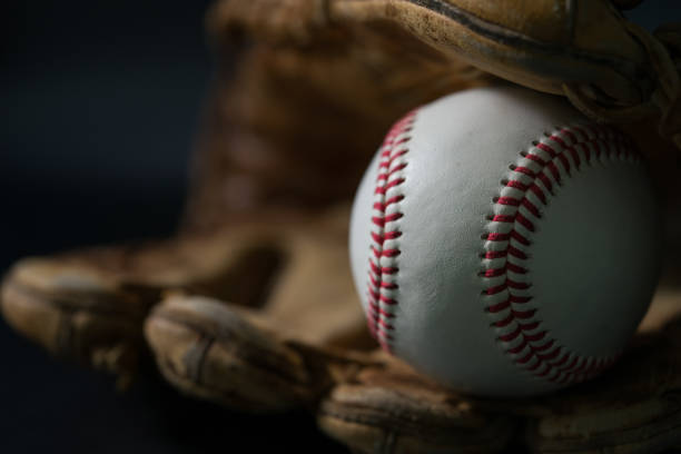 istock Baseball in a glove on black background. 1199190445