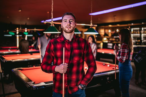Young Caucasian handsome man in a bar playing snooker.