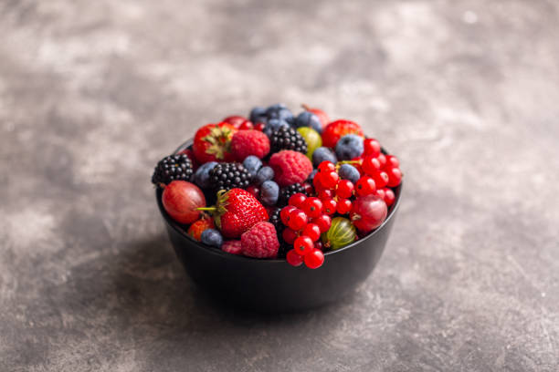 istock Black bowl with fresh summer berries on a gray background. 1199190856