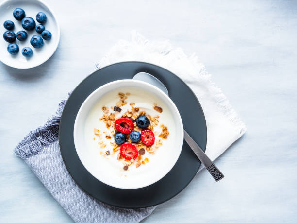 istock Yogurt with raspberries, blueberries and muesli in a white bowl 1199191782