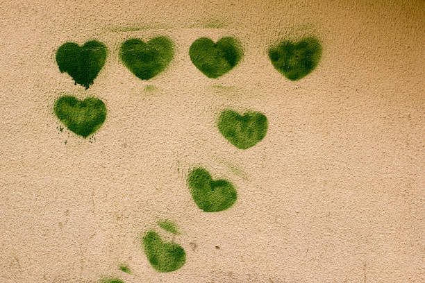 istock Green hearts with painted on the battered stucco wall. 1199195225