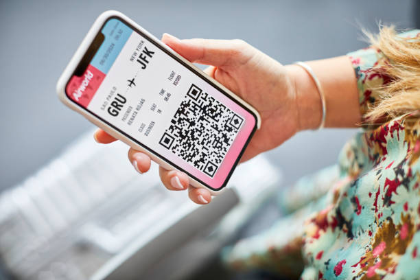 Woman holding online boarding pass in cellphone Midsection of woman holding online boarding pass on mobile phone. High angle view of female using smart phone. She is at airport during travel. airplane ticket photos stock pictures, royalty-free photos & images