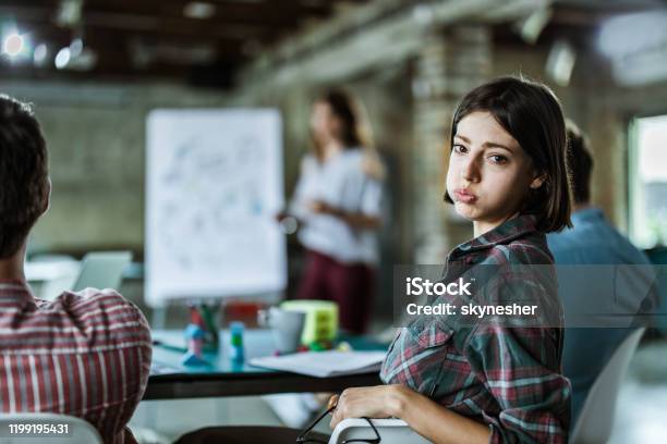 Gelangweilte Kreative Frau Bei Einem Vortrag Mit Ihren Kollegen Im Büro Stockfoto und mehr Bilder von Langeweile