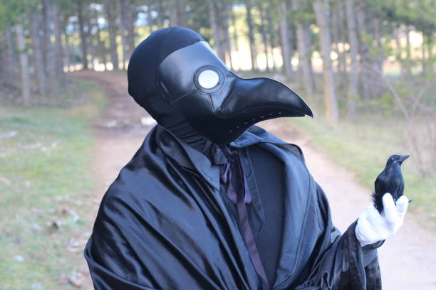 istock Man with crow mask holding a raven 1199196076