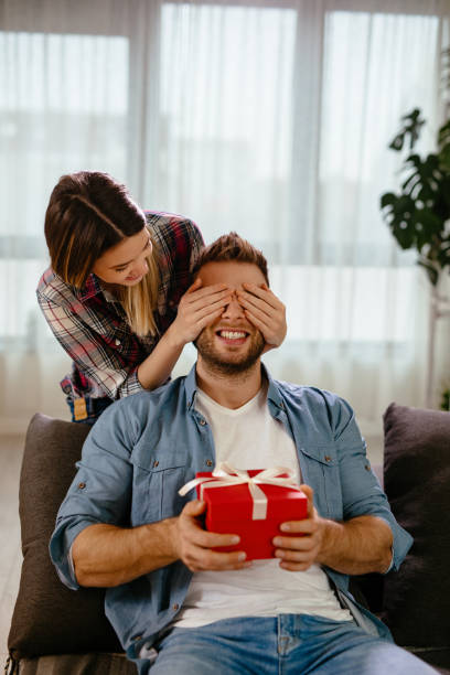 istock Young woman surprising her boyfriend with gift 1199199199