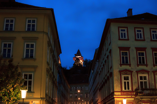 Dark evening city street and illuminated clock tower in Graz, Austria. Grazer Uhrturm by blue night sky