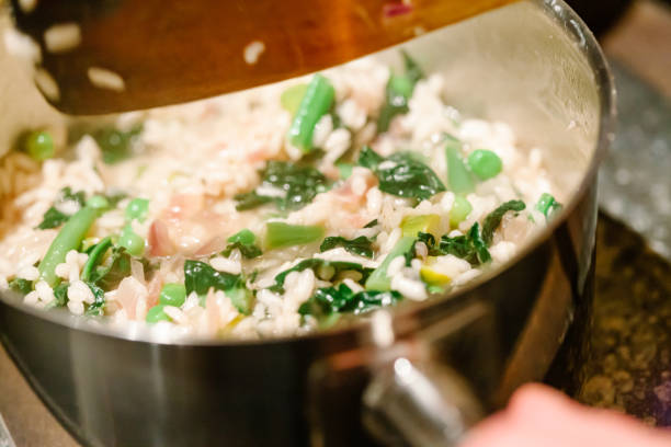 Vegan Risotto Primavera with kale, asparagus and peas cooking on a stove.