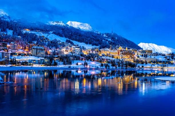 vue des belles lumières de nuit de la ville de rue-moritz en suisse la nuit en hiver, avec la réflexion du lac et des montagnes de neige dans backgrouind - engadine european alps switzerland water photos et images de collection