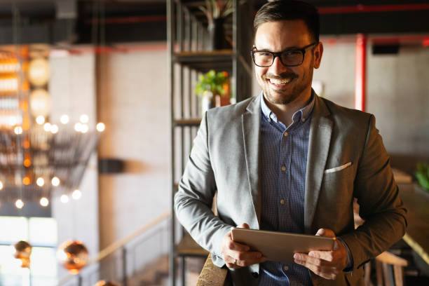 istock Happy businessman dressed in suit in modern office using tablet 1199203279