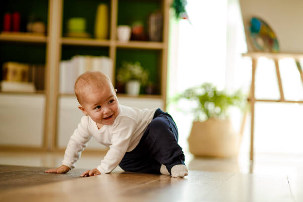 Cute baby girl deciding where to crawl Front view of cute playful baby girl having fun on the floor while being chased by someone. crawling photos stock pictures, royalty-free photos & images