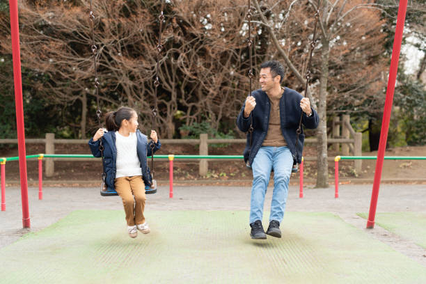 istock 6 year old girl going on swing with her father in park 1199204596
