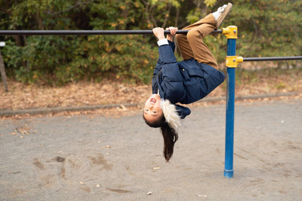 istock Elementary age girl playing with gymnastics bar in park 1199205005