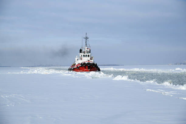 White ship moored in a frozen, snow-covered river, surrounded by a serene winter landscape under a cloudy sky at sunset