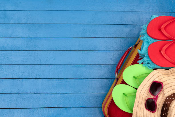 istock Suitcase with flip-flops, hat and sunglasses on wooden table. 1199211996