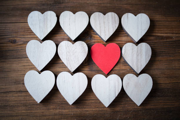 Red heart in white hears - individual concept,large group of hearts shape on wooden background, Valentine`s Day background.